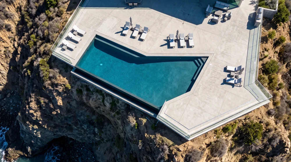 Aerial view of a cliffside infinity pool and deck overlooking the California coast