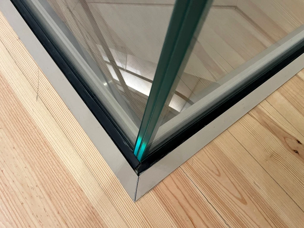 Glass railing panel set in a steel base channel on a hardwood deck floor - deck builder in Northern California - MH Builders