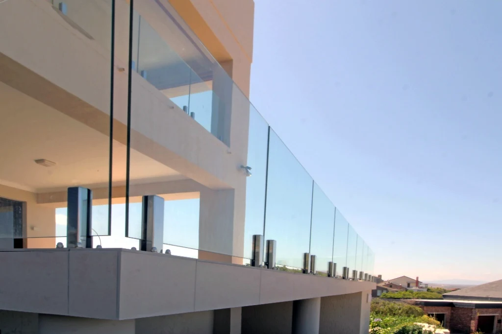 Hillside glass balcony railing with coastal views - custom deck by MH Builders